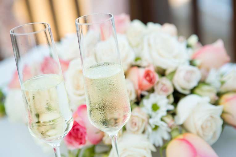Two flutes of champagne in front of Brides bouquet