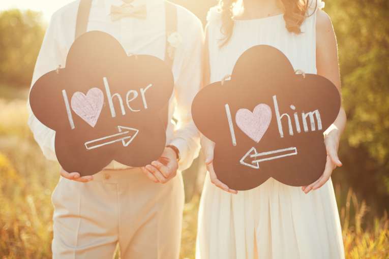 Bride and groom holdings signs at their wedding