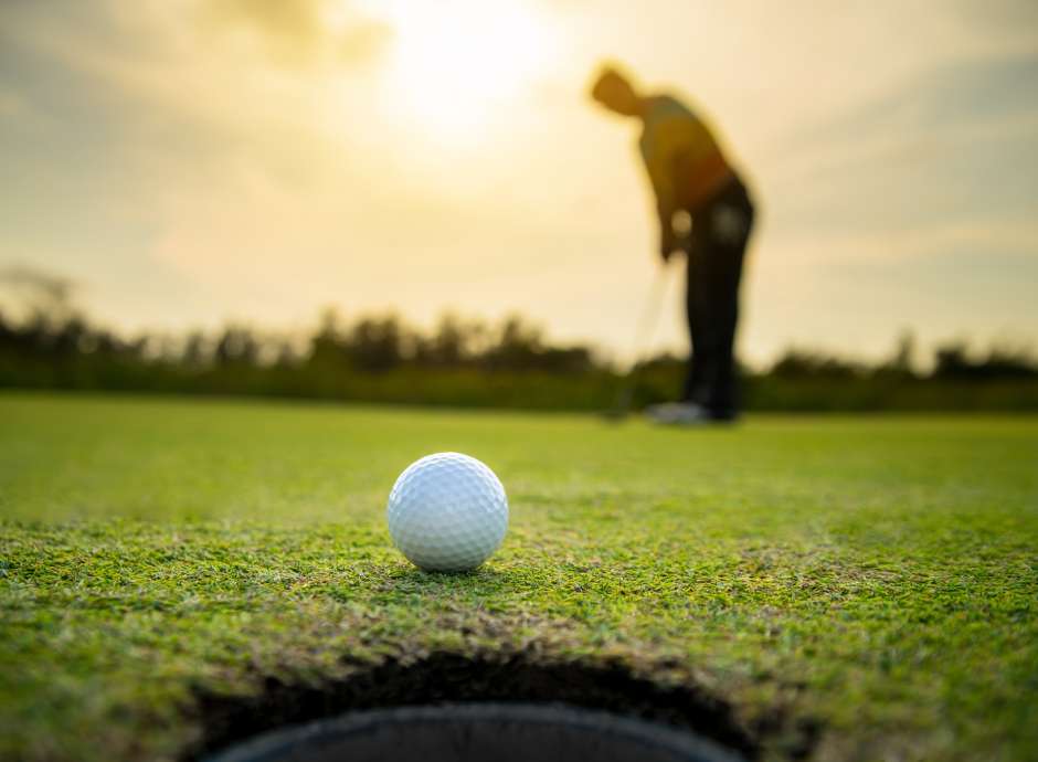 man blurred in background and golf ball in view