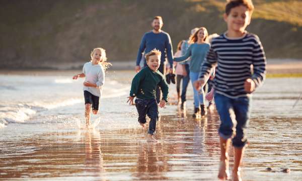 Family running along beach in autumn