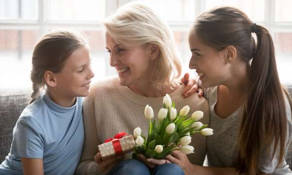 Mother and two daughters holding flower and gift