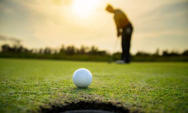 man blurred in background and golf ball in view